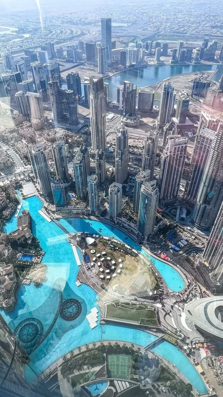This may contain: an aerial view of a large city with lots of tall buildings and blue water in the foreground