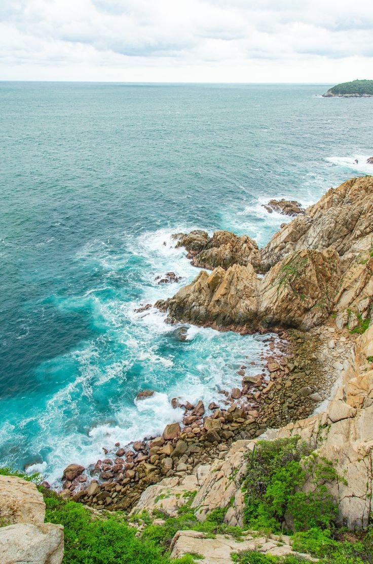 This may contain: the ocean is blue and green with waves crashing on it's rocky shorelines