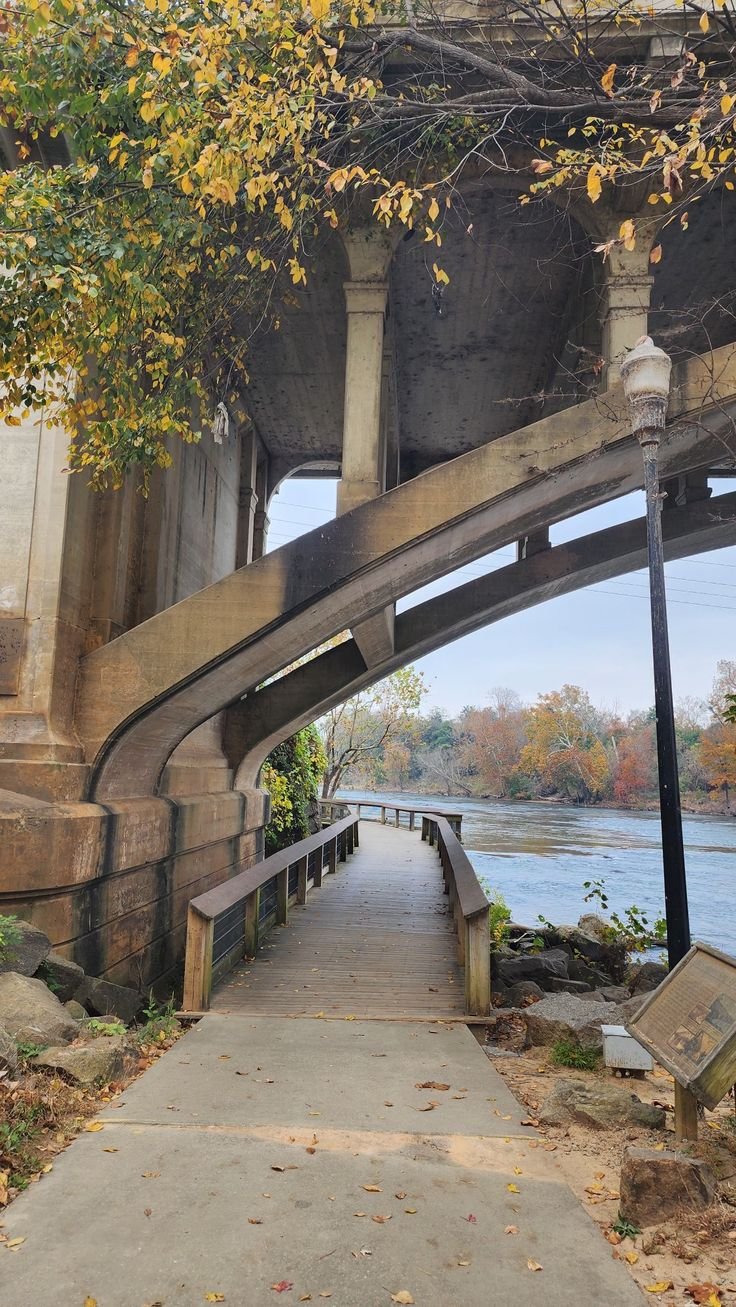 This may contain: the walkway is under an overpass with stairs leading up to it and trees in the background