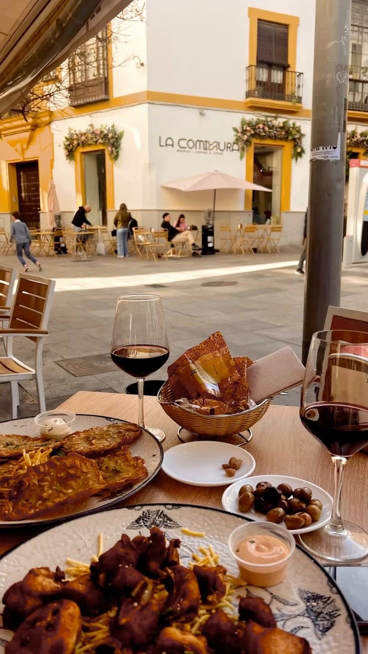 This may contain: a table topped with plates of food and glasses of wine