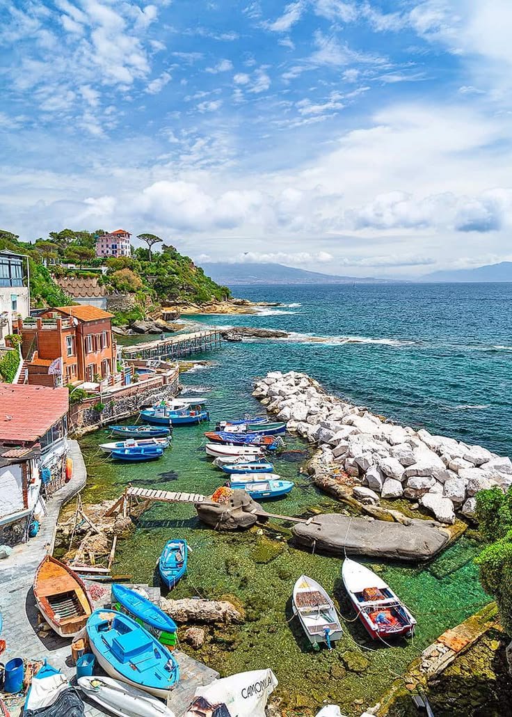 This may contain: there are many boats that are parked on the shore next to the water and rocks