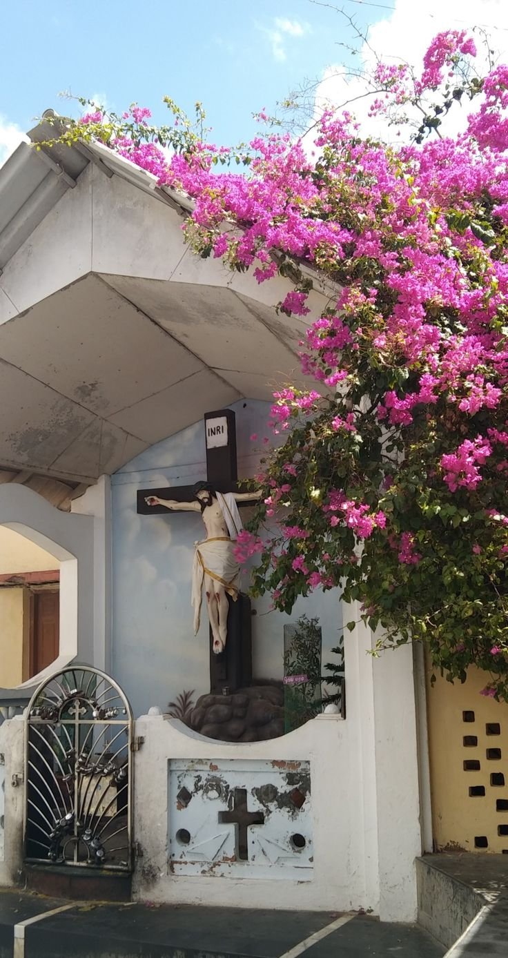 This may contain: a white building with a cross and flowers on it