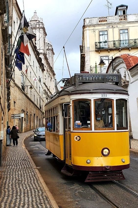 This may contain: a yellow trolley car traveling down a street next to tall buildings
