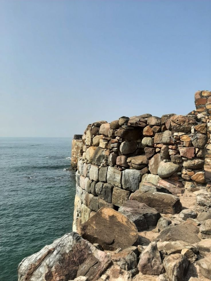 This may contain: an old stone wall next to the ocean