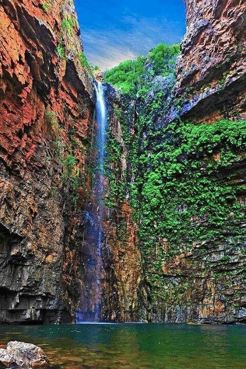 This may contain: a large waterfall in the middle of a canyon