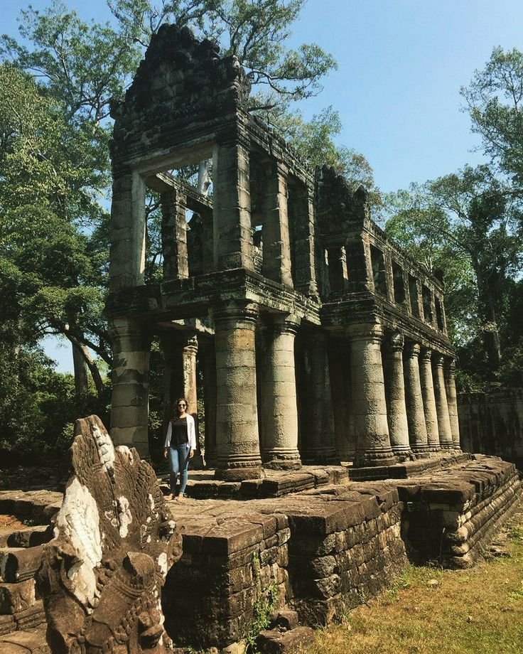 This may contain: an ancient building in the middle of a forest with people standing around it and looking at something