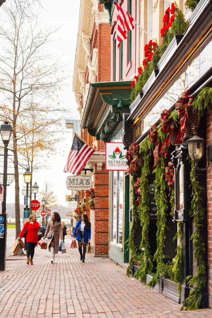 This may contain: people are walking down the street in front of shops with christmas decorations on their windows
