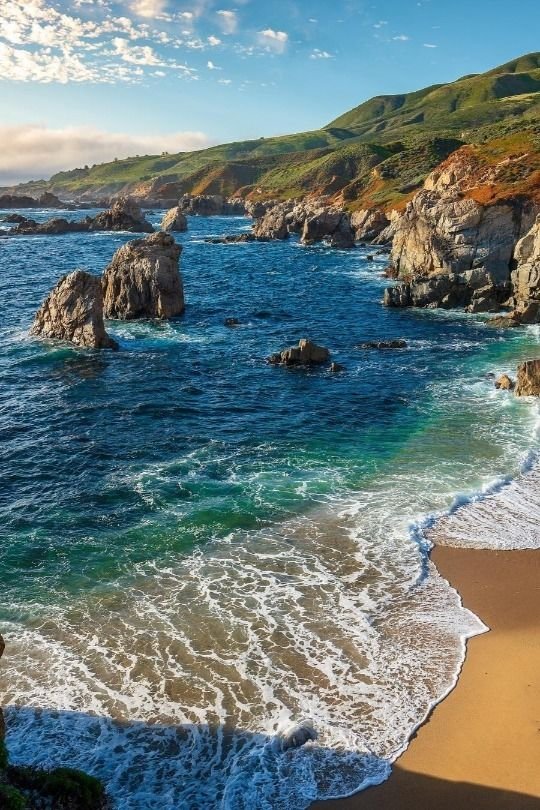This may contain: the beach is surrounded by large rocks and water