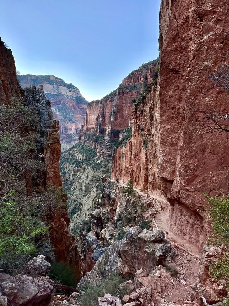This may contain: a narrow canyon filled with lots of rocks and trees on the side of a mountain