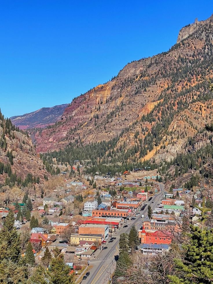 This may contain: a town nestled in the mountains surrounded by trees