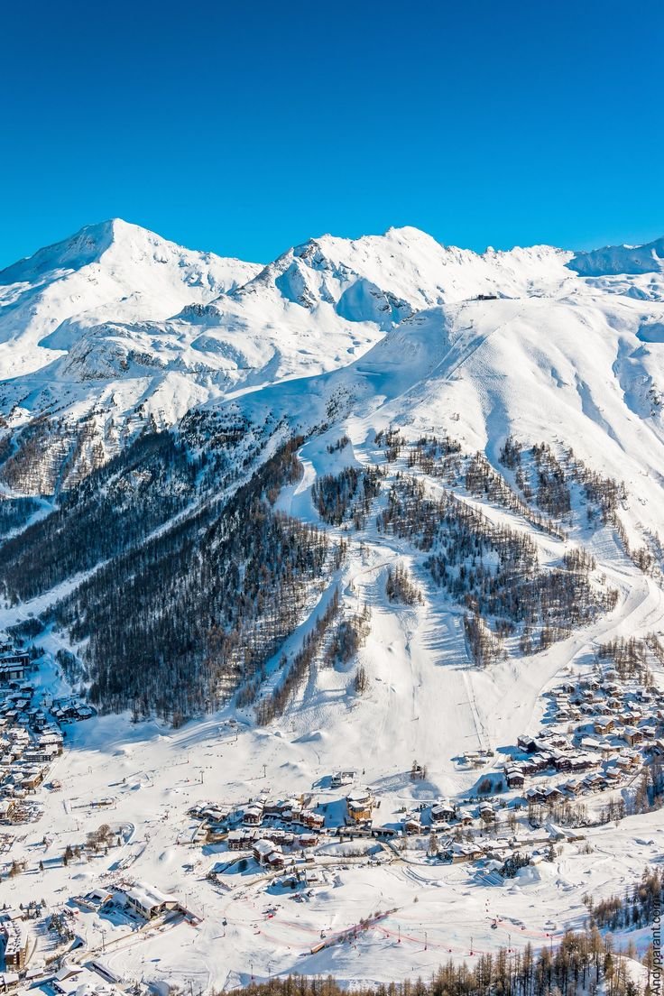 This may contain: an aerial view of a ski resort with mountains in the background and snow on the ground