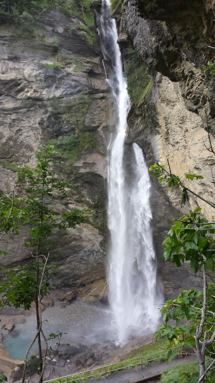 This may contain: a large waterfall in the middle of a forest