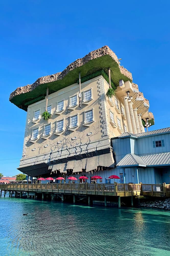 This may contain: a large building sitting on the side of a body of water next to a pier