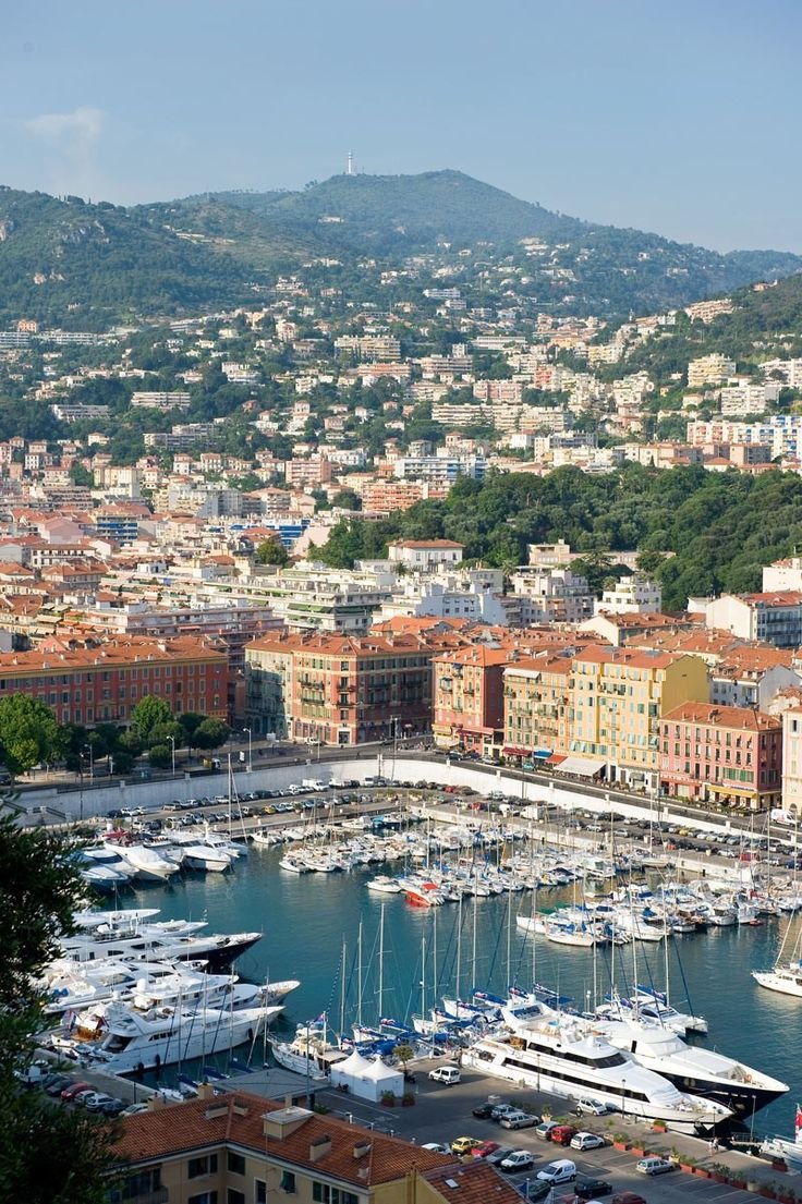 This may contain: boats are docked in the harbor next to some buildings and hills with trees on them