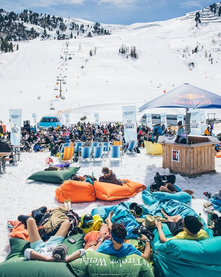 This may contain: people are lounging on bean bags in the snow while others watch from behind them