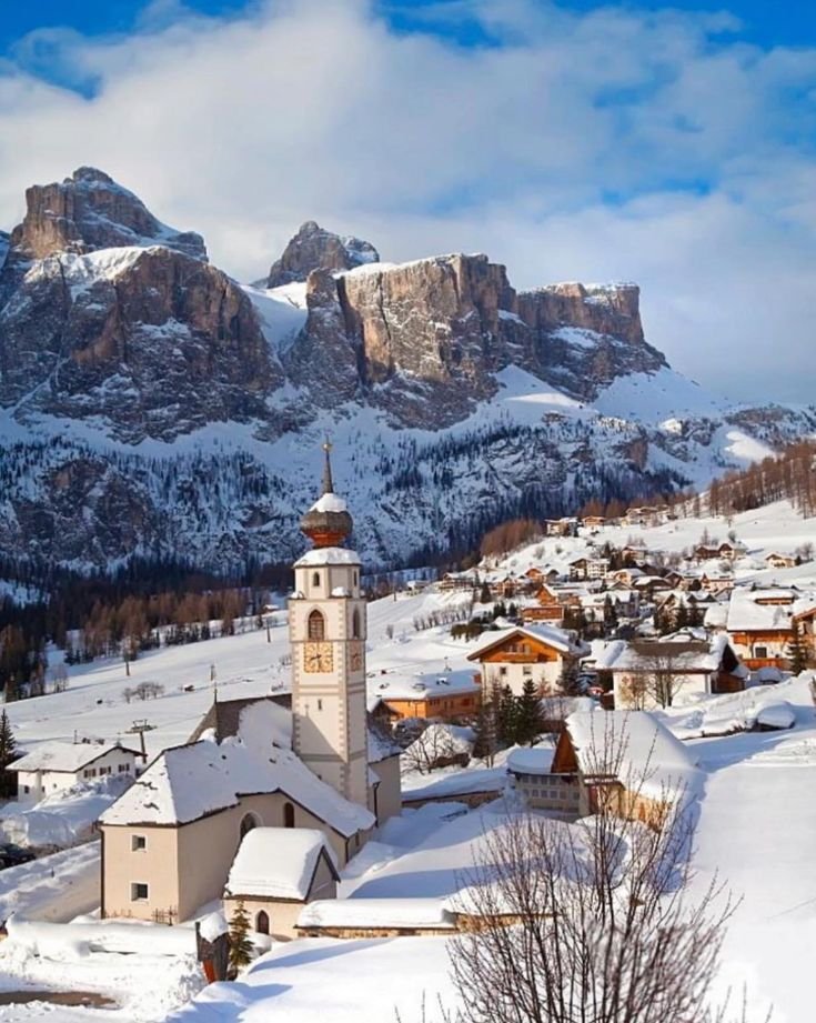 This may contain: an alpine village with snow covered mountains in the background