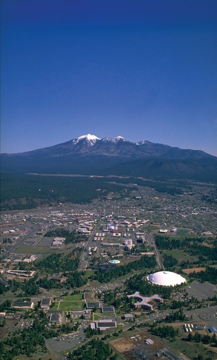 This may contain: an aerial view of a city with snow capped mountains in the backgrouds