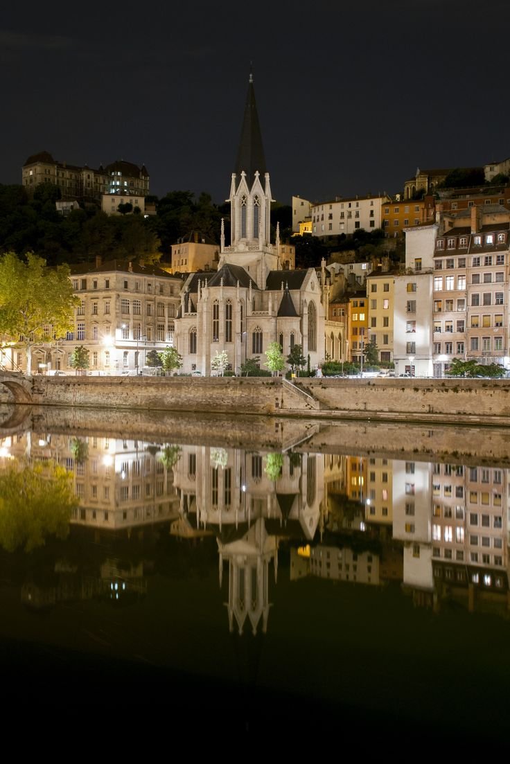 This may contain: a large building sitting next to a body of water in front of a city at night