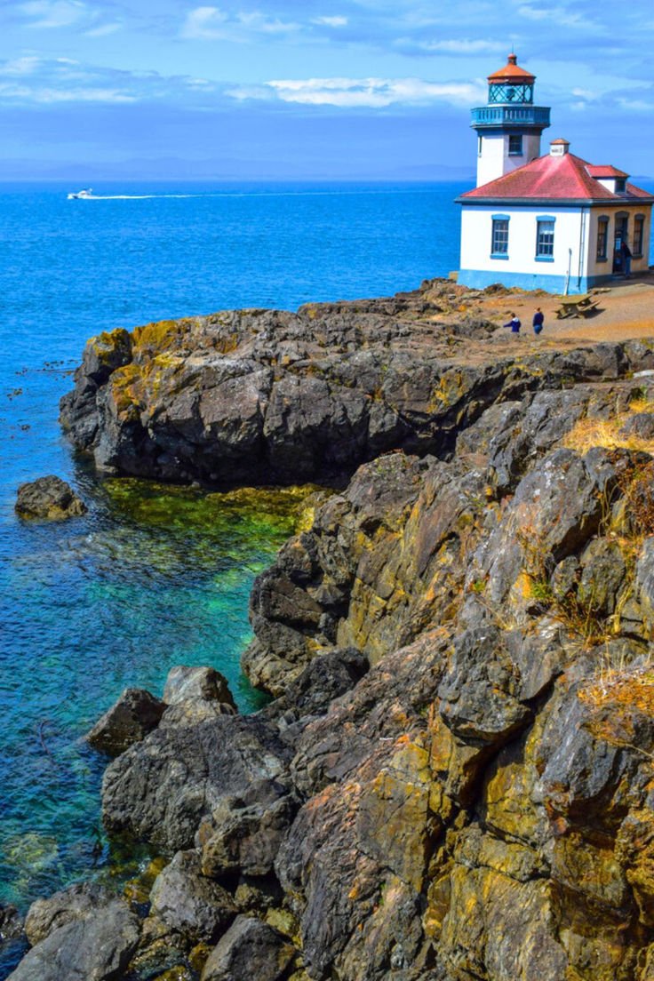 This contains: The Lime Kiln Lighthouse perched on a rugged cliff in the San Juan Islands Washington.