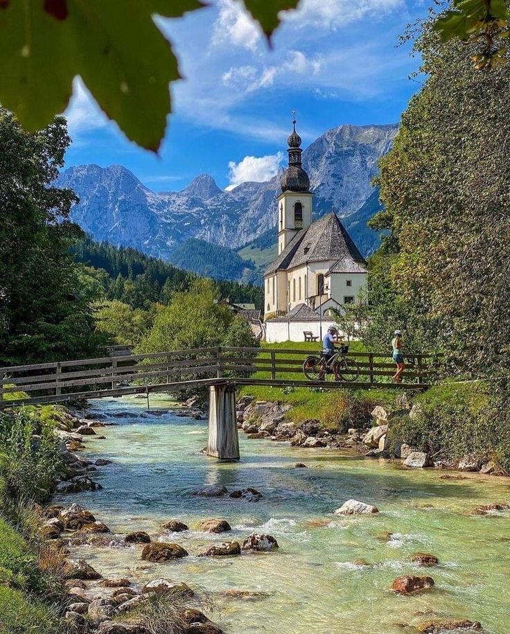 This may contain: a small church in the middle of a river with mountains in the backgroud