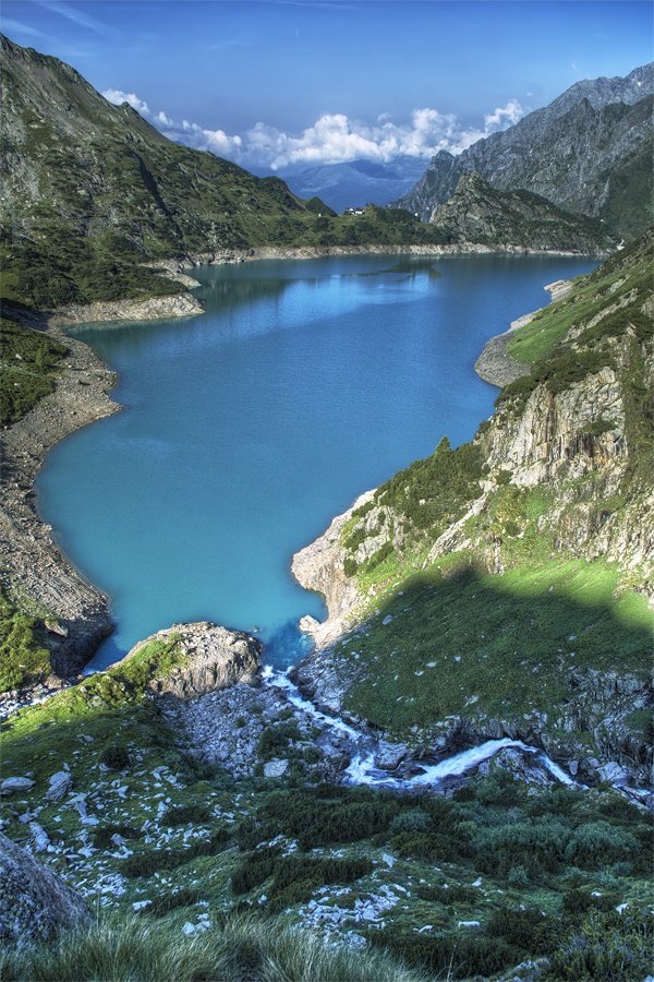 This may contain: a large body of water surrounded by mountains and greenery in the foreground is a blue lake