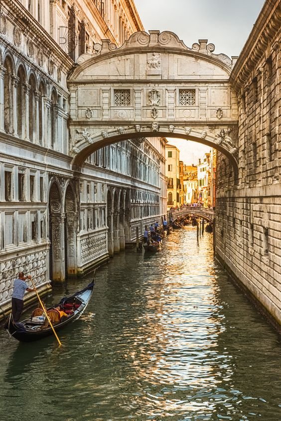 This may contain: a gondola in the middle of a canal under a bridge