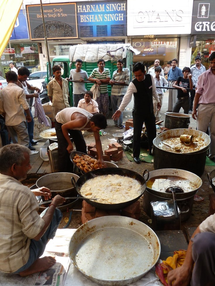 This may contain: many people are gathered around some pans with food in them