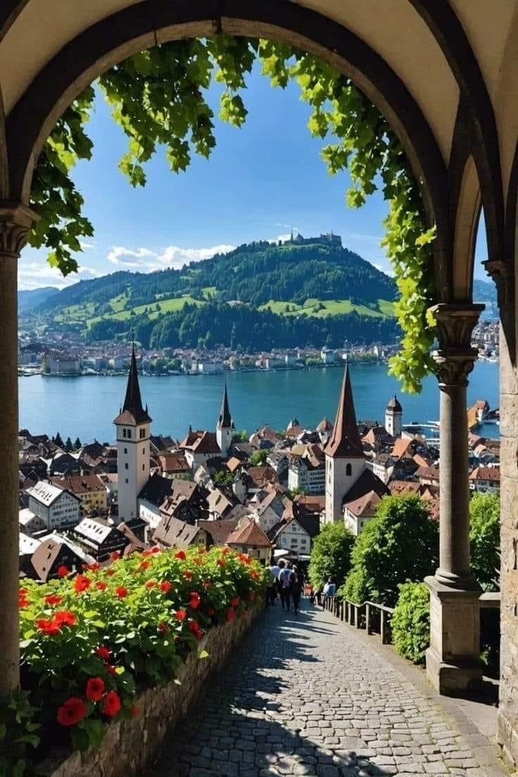 This may contain: an archway leading to a town with flowers in the foreground