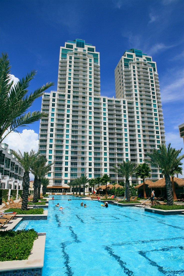 This may contain: people are swimming in an outdoor pool next to tall buildings
