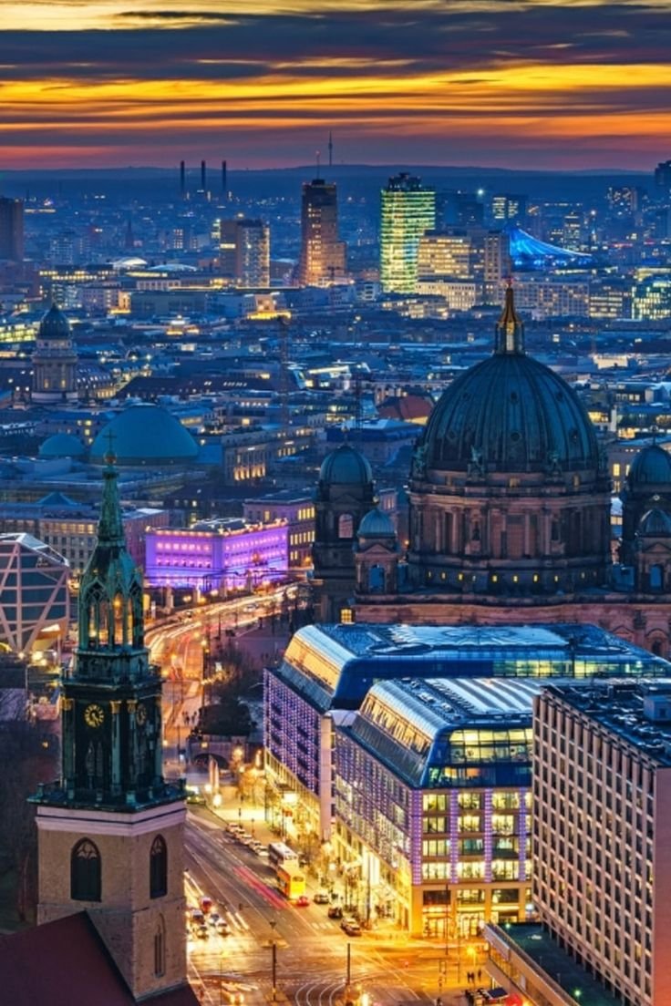 This may contain: the city skyline is lit up at night, with many buildings in the foreground