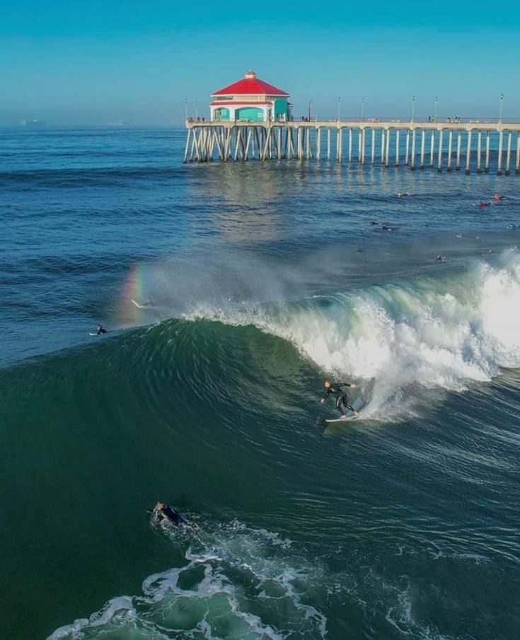 This may contain: people are surfing in the ocean near a pier