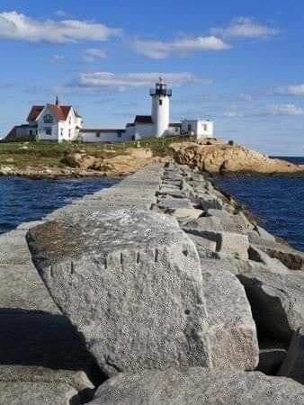 This may contain: there is a light house that is on top of the rock wall by the water