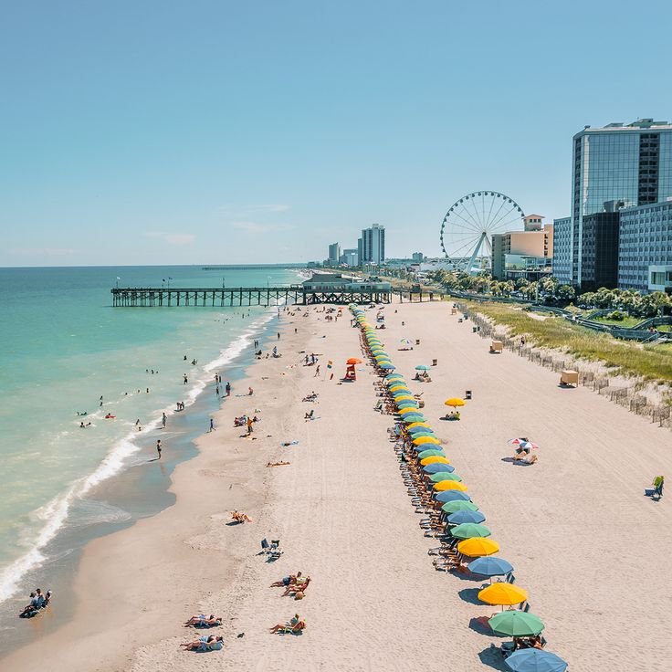 This may contain: the beach is crowded with people and umbrellas