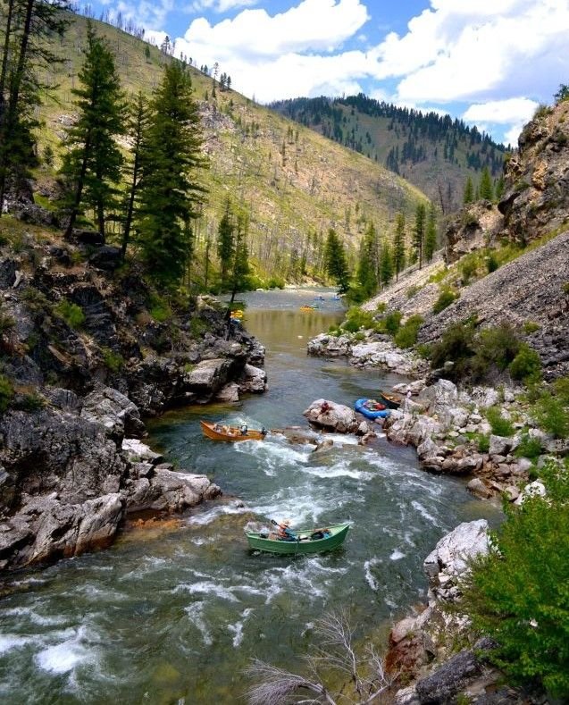 This may contain: several canoes are in the water near some rocks