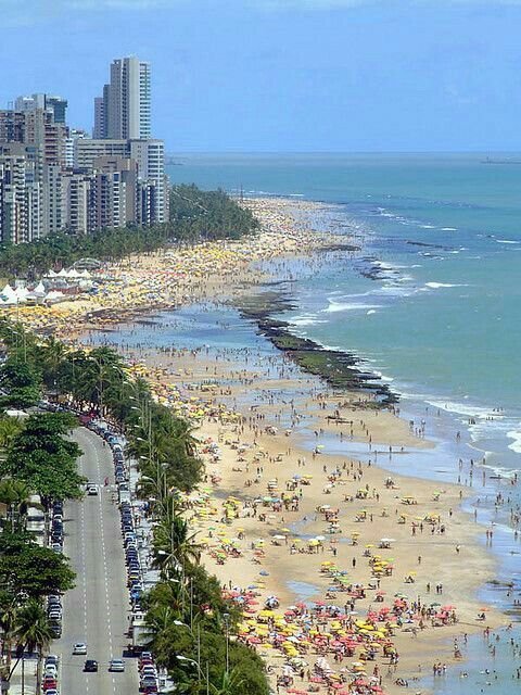 This may contain: the beach is crowded with people and cars