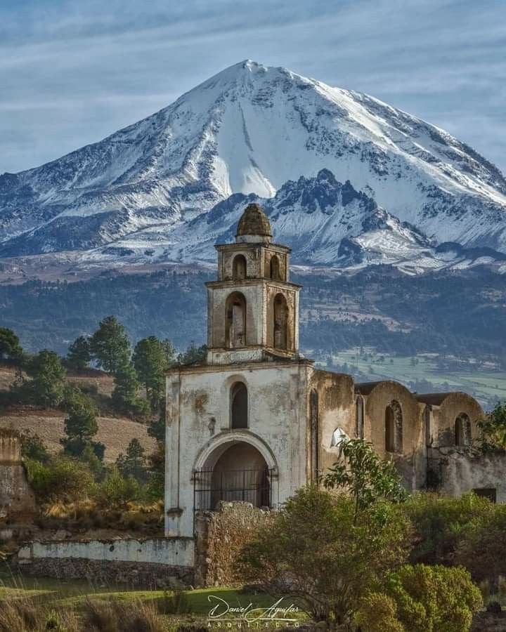 This may contain: an old church in the foreground with a snow - capped mountain in the background