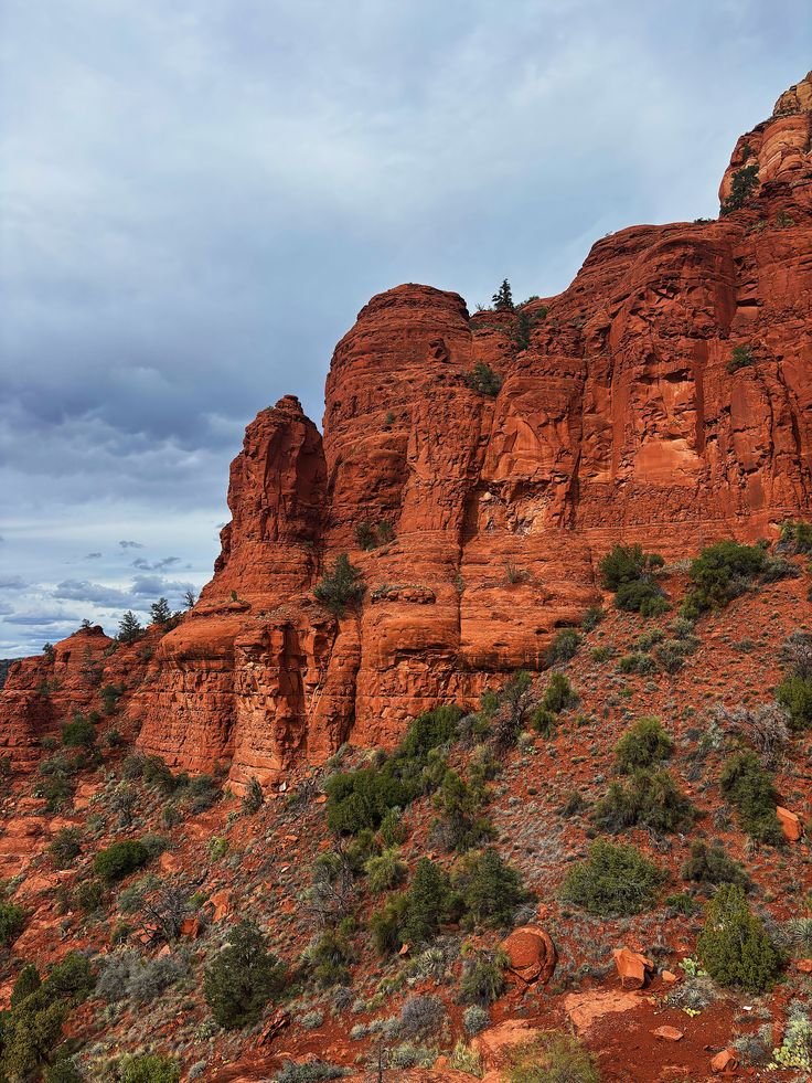 This may contain: red rock formations with trees and bushes on the side