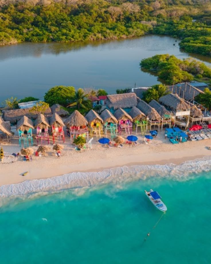 This may contain: an aerial view of a beach resort with thatched huts and boats in the water