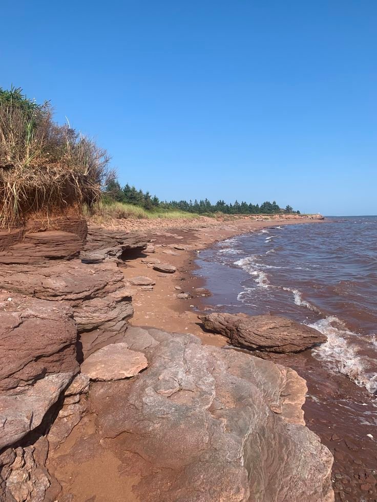 This may contain: the beach is lined with large rocks and water