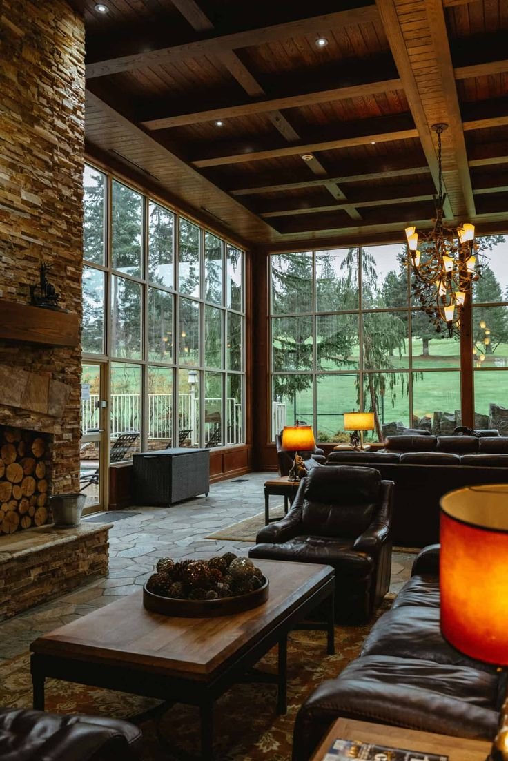 This may contain: a living room with couches and tables in front of large windows that look out onto a grassy field
