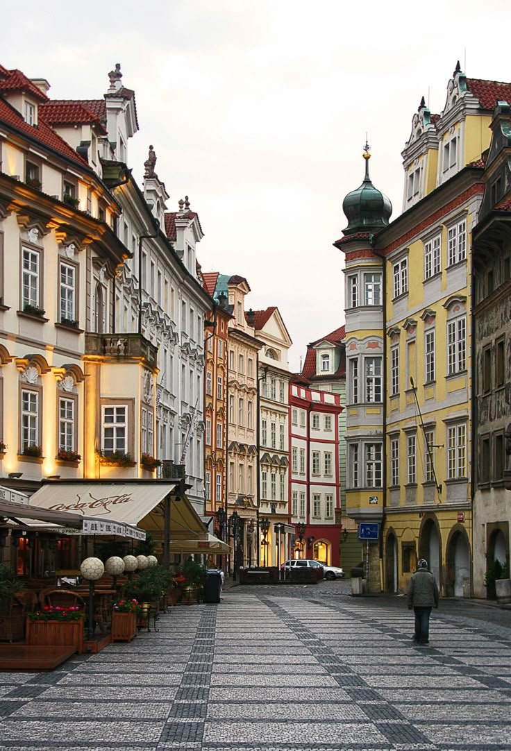 This may contain: an empty city street with many buildings and people walking on the sidewalk in front of it