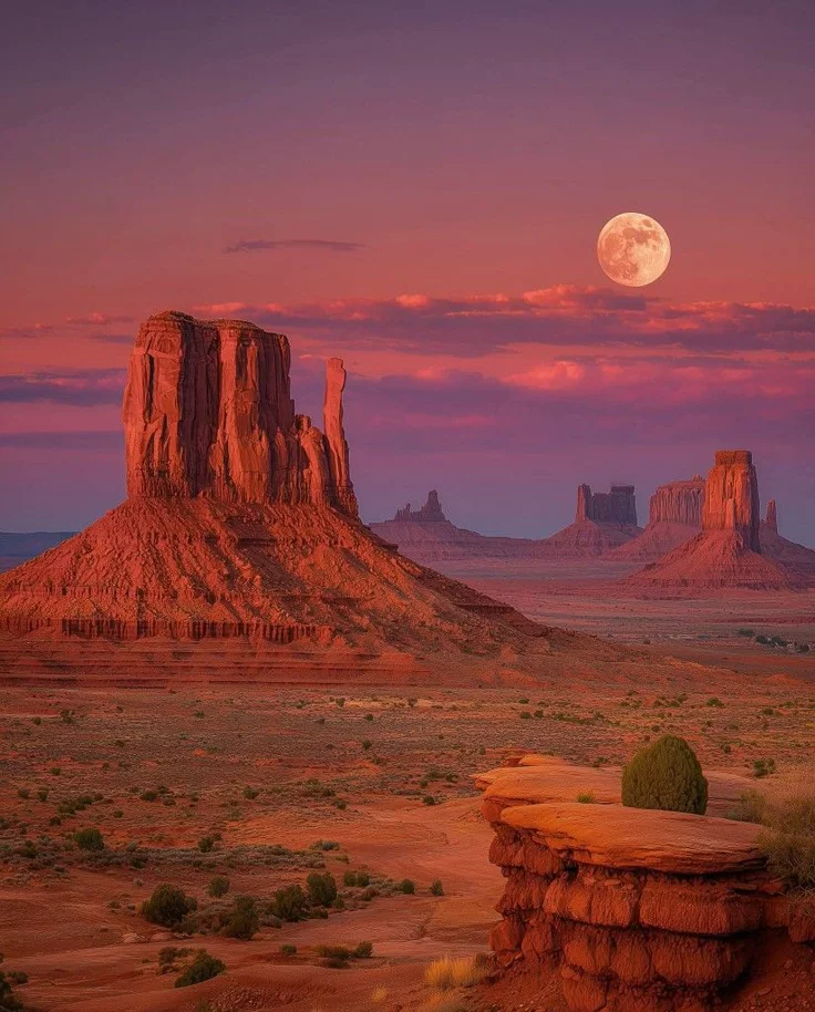 This may contain: the full moon is setting over monument buttes in monument national park, arizona usa
