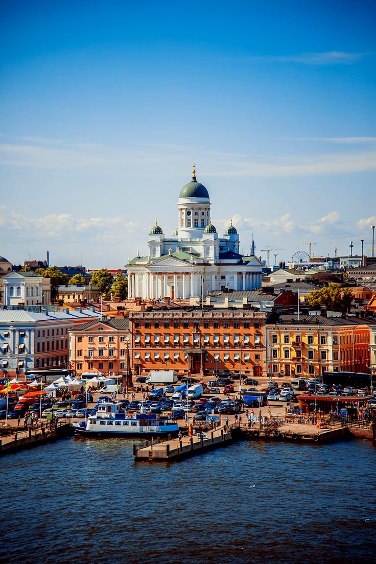 This may contain: boats are docked in front of the buildings on the water's edge, with a domed building in the background