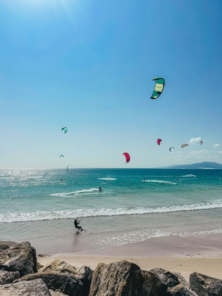 This may contain: people parasailing in the ocean on a sunny day with blue sky and clear water