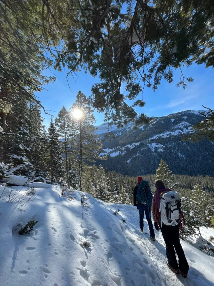 This may contain: two people walking up a snow covered hill