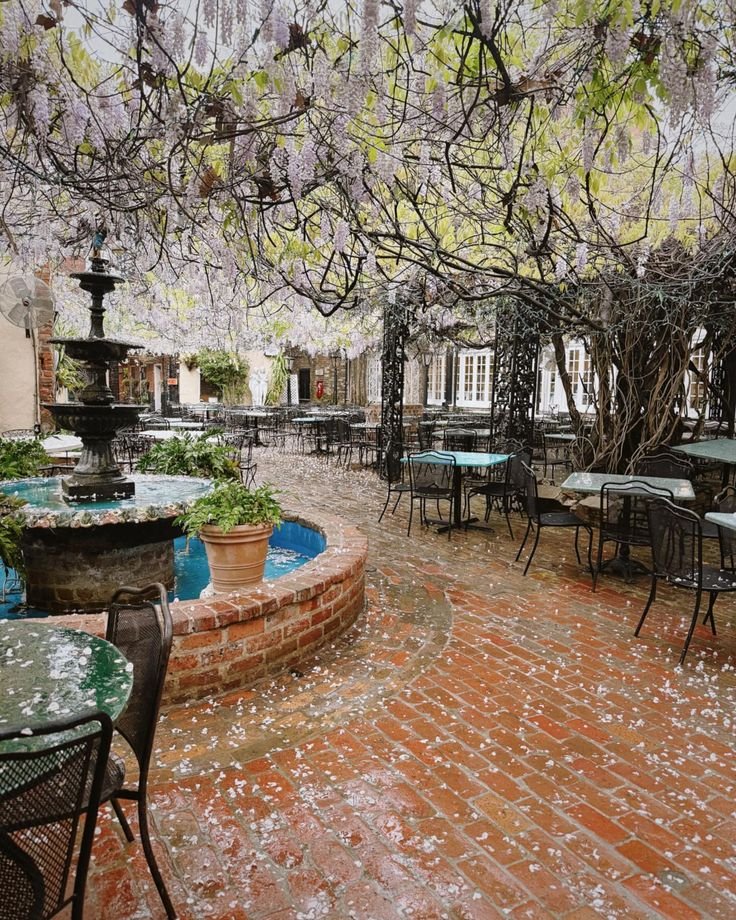 This may contain: an outdoor dining area with tables, chairs and a fountain in the middle of it
