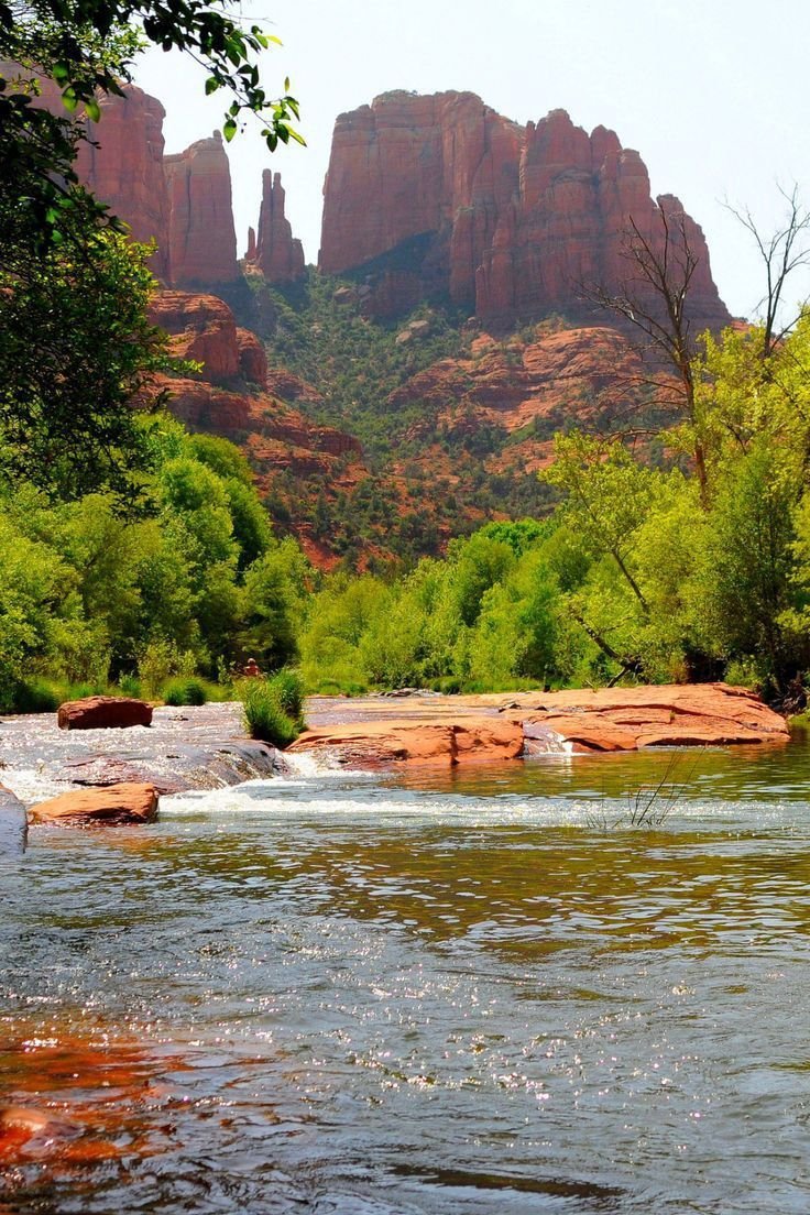 This may contain: there is a river that runs through the mountains with rocks in the water and trees around it