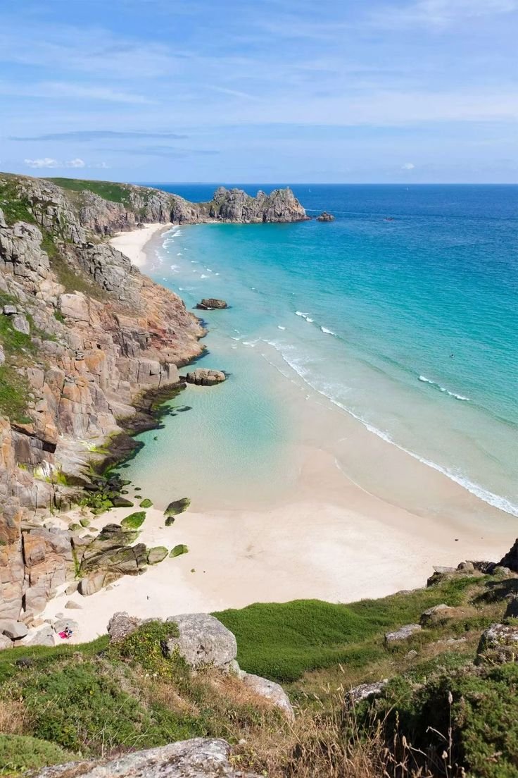 This may contain: the beach is surrounded by rocky cliffs and blue water