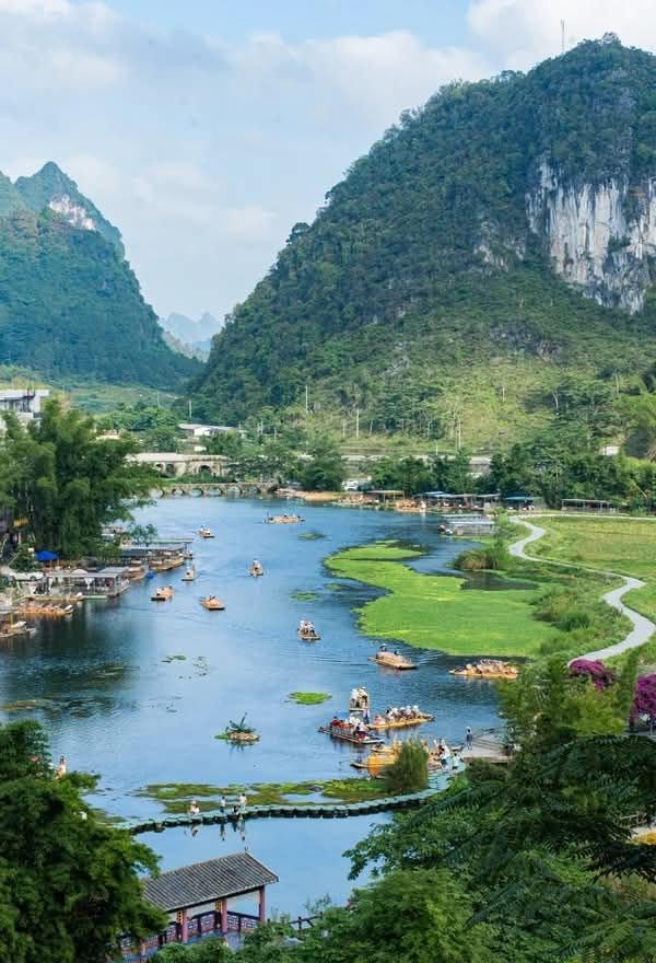 This may contain: boats are floating on the river in front of mountains