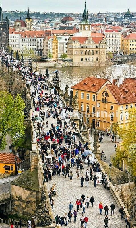 This may contain: many people are walking up and down the stairs in this old city with tall buildings